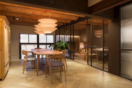 Warm, rustic dining space with wooden furniture, pendant lights, and floor-to-ceiling windows.