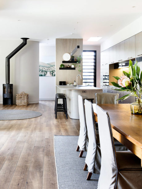 Modern open-plan kitchen-dining area with wood floors, neutral tones, and stylish decor.