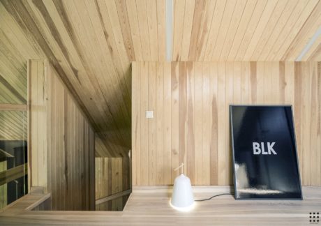 A cozy wooden interior with a minimalist black and white lamp and framed artwork.