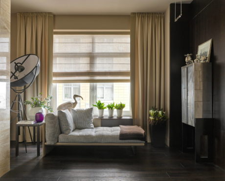 Cozy window nook with plush cushions, potted plants, and a standing lamp in a modern interior.