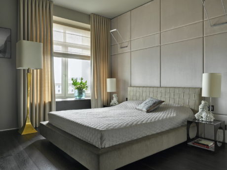 Spacious bedroom with modern gray tones, plush bedding, and a large window.