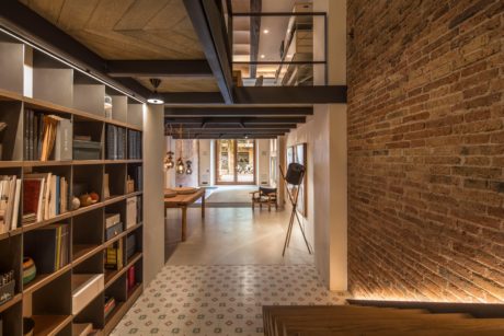 A modern, industrial-style hallway with exposed brick walls, wooden beams, and a patterned tile floor.