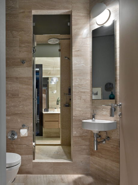 Elegant bathroom with sleek modern fixtures, recessed lighting, and textured stone walls.