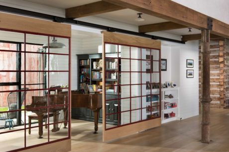 Rustic interior with wooden beams, glass-paneled doors, and book-filled