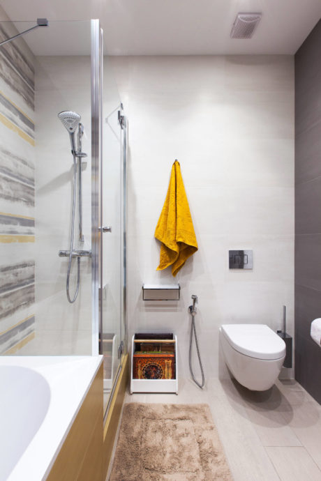 Modern bathroom with sleek shower, storage cabinet, and vibrant yellow towel.