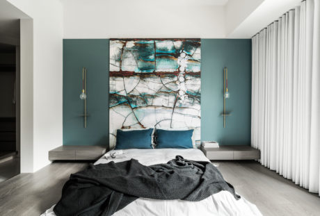 Contemporary bedroom with abstract artwork, floating nightstands, and pendant lighting.