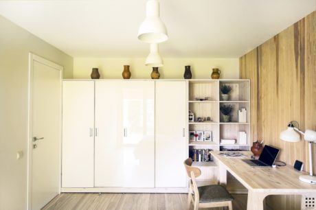Minimalist workspace with white built-in cabinetry, wooden accents, and a large desk.