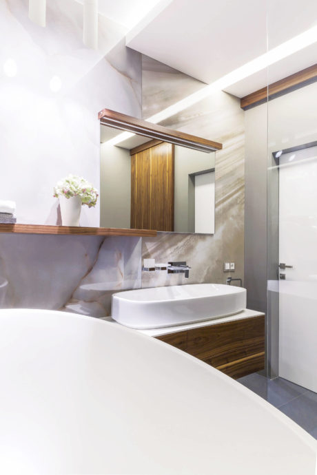 Sleek modern bathroom with marble-like walls, wooden vanity, and vessel sink.
