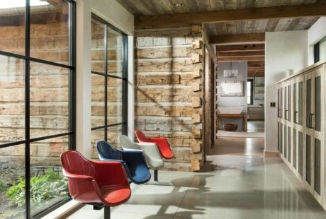 Rustic interior with reclaimed wood walls and colorful mid-century chairs.