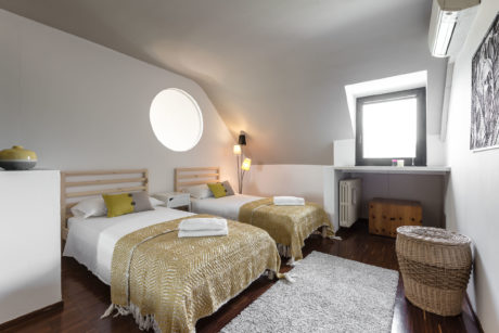 Well-lit attic bedroom with wood and neutral-toned decor, creating a cozy ambiance.