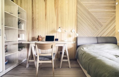 A cozy, minimalist bedroom with a wooden desk, shelves, and textured walls, creating a serene atmosphere.