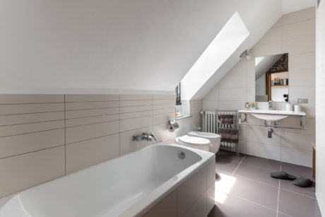 A modern bathroom with sleek, minimalist design and ample natural light from a skylight.
