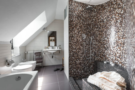Elegant bathroom with mosaic tile walls, modern vanity, and walk-in shower.