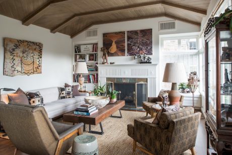 Cozy living room with fireplace, exposed beams, and eclectic decor.