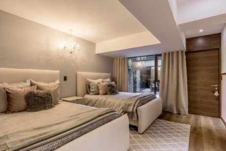 Elegant bedroom interior with neutral tones, plush bedding, and modern lighting.