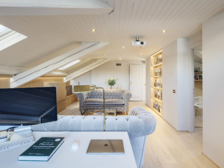 Sleek attic office with elegant sitting area and built-in bookshelf.