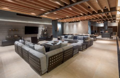 Modern living room with large sectional sofa and exposed wooden ceiling beams.