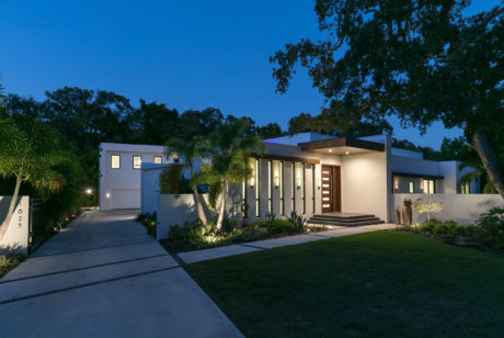 Contemporary white home exterior at dusk with accent lighting.