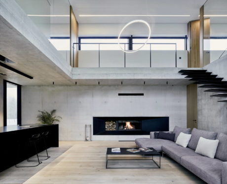 Modern living room with concrete walls, large sofa, and circular light fixture.