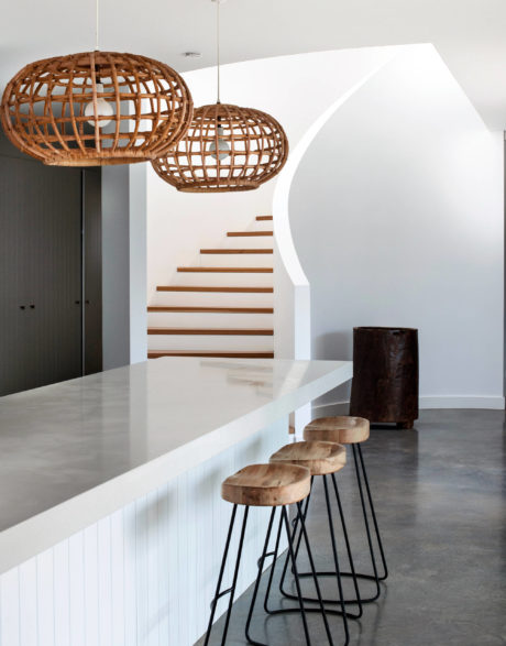 Modern interior with wooden pendant lights, white counters, bar stools, and arched