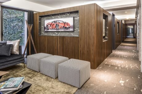 Modern hallway with wooden panels, artwork, patterned cubes seats, and a couch