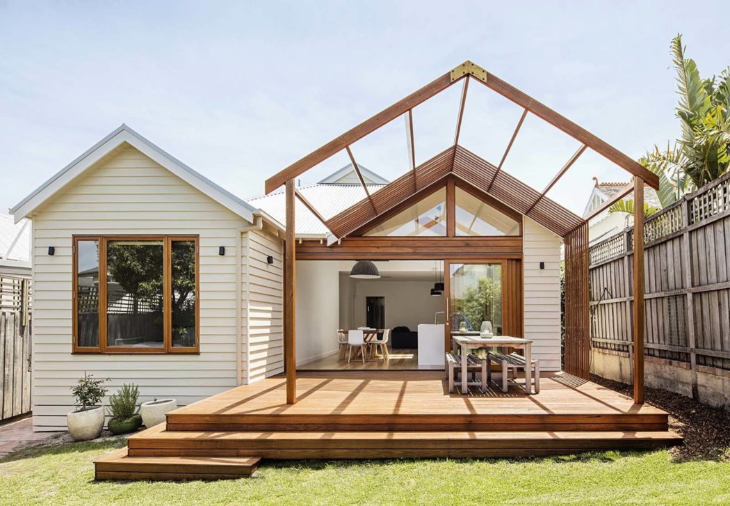 Contemporary house extension with a gabled glass roof and wooden deck.