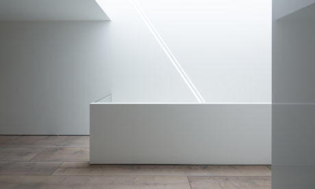 Minimalist interior with white walls, wooden floor, and natural light.
