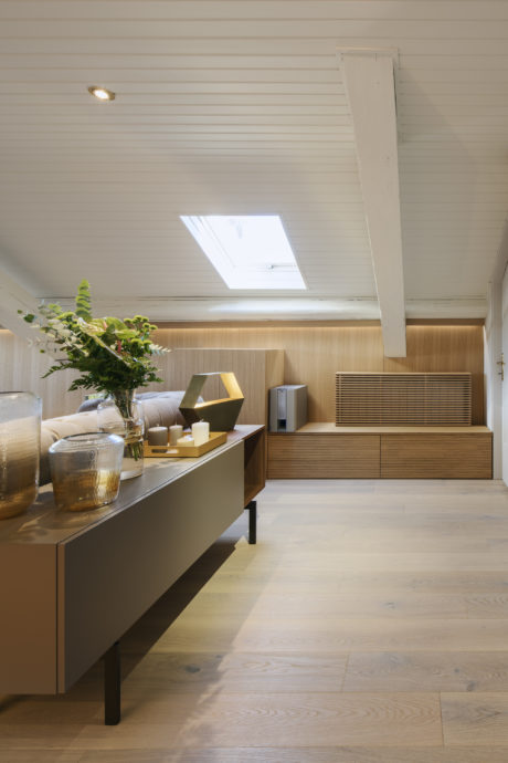 Modern attic room with skylight, wooden floors, and decorative sideboard.