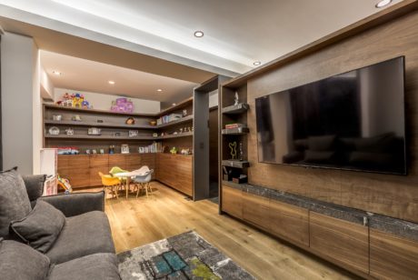 Modern living room with sectional sofa, wall-mounted TV, and play area.