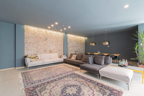 Modern living room with a sectional sofa, brick wall accent, and Persian rug.