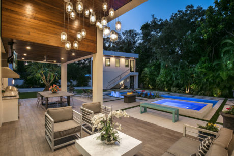 Elegant outdoor patio with hanging lights, fireplace, and pool.