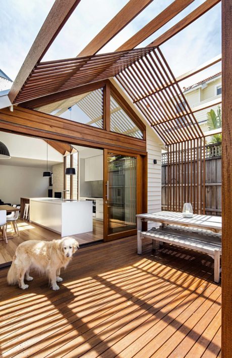 Modern patio with wooden decking and pergola, including a dog.