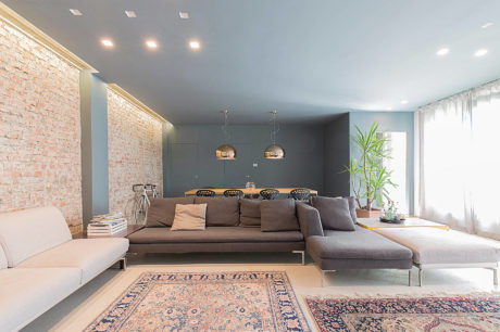 Modern living room with gray sectional sofa, exposed brick wall, and patterned rugs