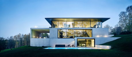 Modern house with large glass windows at dusk.
