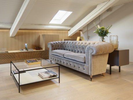 Elegant attic lounge with chesterfield sofa and wooden finishes.