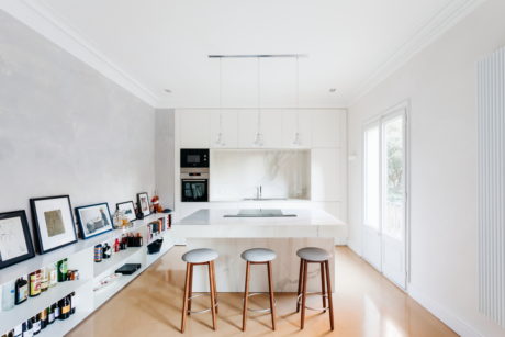 Modern kitchen interior with white cabinets and bar stools.
