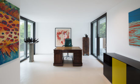 Modern office room with art on walls, wooden desk, chair, and sleek decor