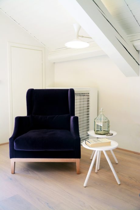 Cozy corner with a navy blue armchair and a small white side table.