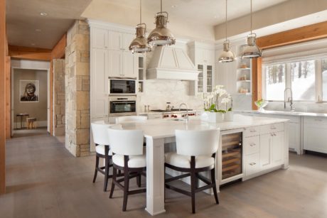 Contemporary kitchen with white cabinetry, stone columns, and pendant lighting.