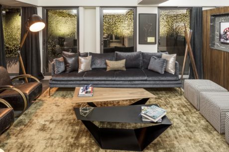 Modern living room with large sofa, geometric coffee table, and designer lamps.