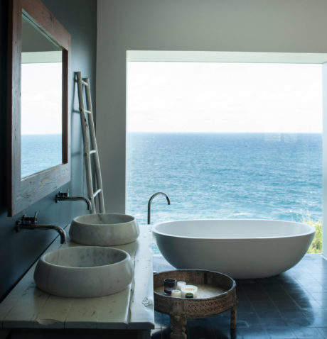 Minimalistic bathroom with ocean view, freestanding tub, and dual sinks.