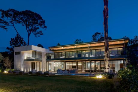 Contemporary house with expansive glass walls and evening lighting.