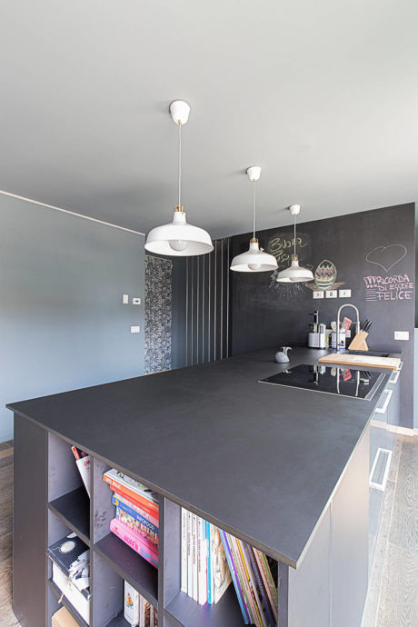 Modern kitchen with a black island, chalkboard wall, and pendant lights.