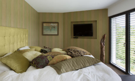 Contemporary bedroom with textured walls, plush bedding, and a wall-mounted TV.