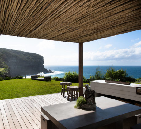 Coastal patio with wooden overhang and ocean view.