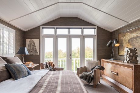 Contemporary bedroom with vaulted ceiling, large windows, and wooden accents.