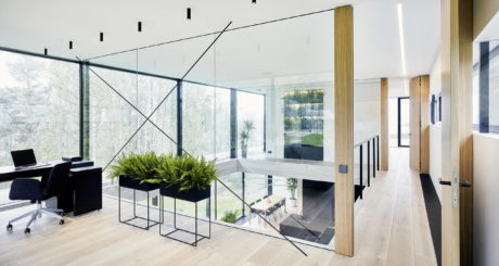 Contemporary office with glass walls and wooden floors.