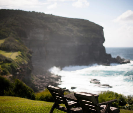 Wooden bench overlooking a cliff and rough sea.