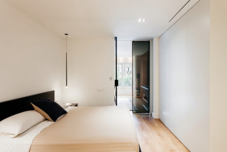 Minimalist bedroom with white walls and wooden floor.