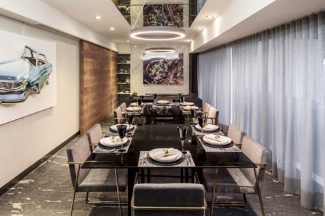 Modern dining room with a long table set for dinner, artwork on the walls,
